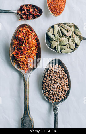 top view of different spices in spoons on white table Stock Photo