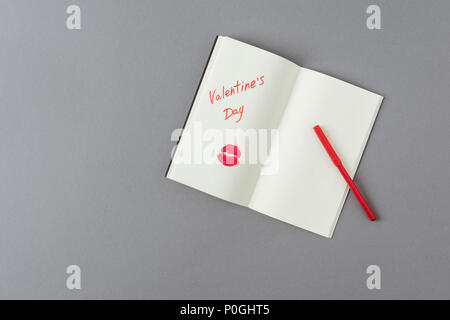 top view of open notebook with note and lips print on gray surface Stock Photo