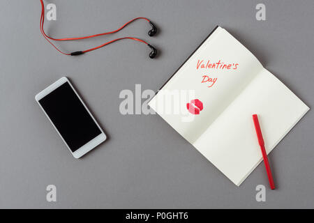 top view of smartphone and notebook with lips print on gray surface Stock Photo