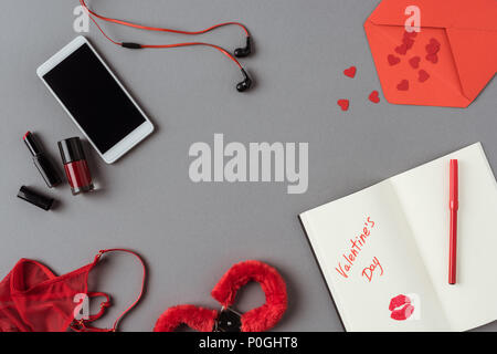 top view of smartphone, notebook with lipstick and handcuffs on gray surface Stock Photo