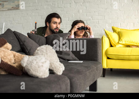 father and daughter playing with toy gun and binoculars at home Stock Photo