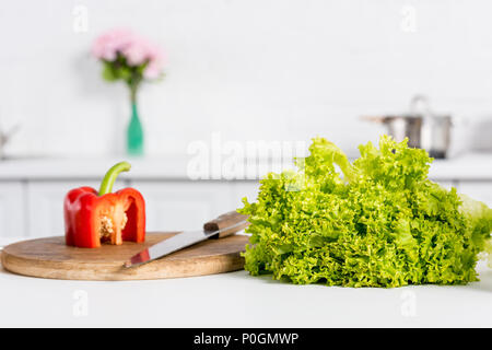 bell pepper and lettuce on wooden board with knife in kitchen Stock Photo