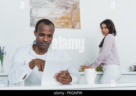 african american girlfriend cooking and boyfriend using tablet at kitchen Stock Photo