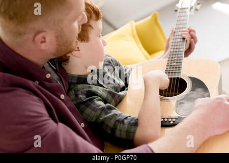 cropped shot of father teaching little son playing acoustic guitar