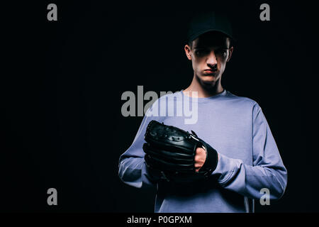 Man in baseball cap wearing baseball mitt isolated on black Stock Photo
