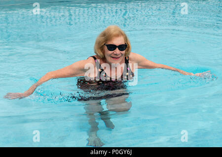 Senior female woman exercising in an outdoor swimming pool; south central Florida; USA Stock Photo