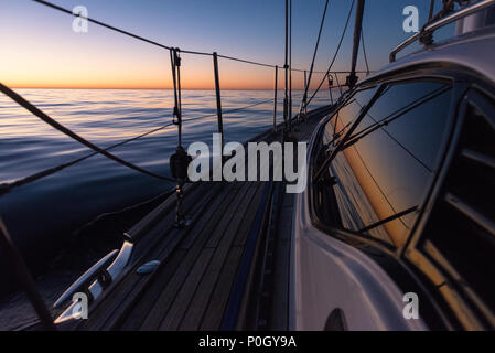 A cruising yacht motoring in calm seas as the sun sets, on passage in the South Atlantic off the coast of South Africa