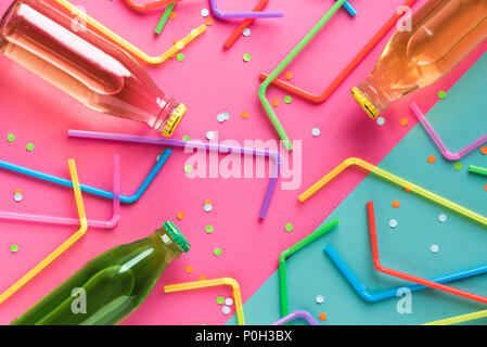 Various cold drinks with straws and confetti on pink and blue background. Summer party, happy vacation and fun concept, top view.