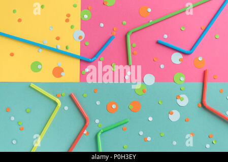 Vibrant confetti and straws on pastel pink, blue, yellow background. Festive multicolored backdrop for your design, copy space. Stock Photo