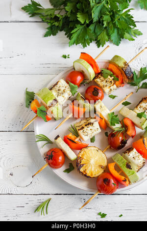 Vegetarian grilling. Vegetarian skewers with halloumi cheese and vegetables on white background, copy space. Stock Photo