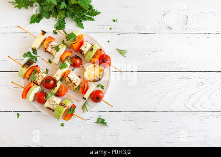 Vegetarian grilling. Vegetarian skewers with halloumi cheese and vegetables on white background, copy space. Stock Photo