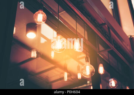 Decorative antique edison style light bulbs against cafe wall background Stock Photo
