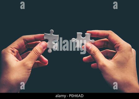 Close up of hand placing the last jigsaw puzzle piece, Hand holding missing jigsaw puzzle piece down in to the place, conceptual of problem solving, f Stock Photo