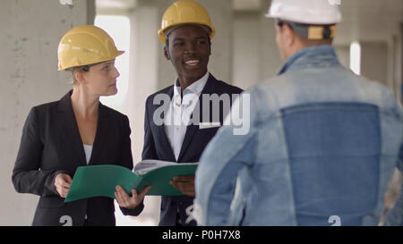 Workgroup of builders looking at new project and discussing it Stock Photo