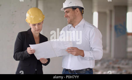 Two architects wearing protective helmet works at building site Stock Photo