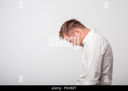 sad european caucasian young man in white shirt looking down Stock Photo