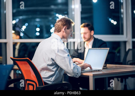 Two gentlemen staying up late in office working. Stock Photo