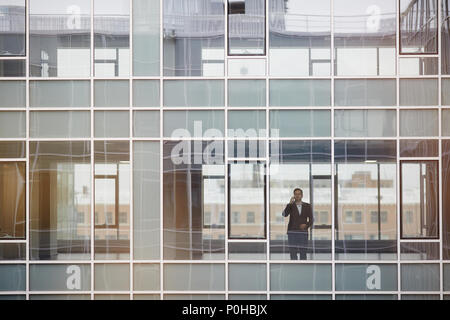 Businessman talking on cell phone near the window at glass modern office Stock Photo