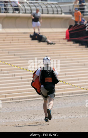 Blackpool, Lancashire, UK. 9 June 2018.  People rush to the aid of an injured base jumper who has crashed into the seaside promenade after a 400ft jump from a hired crane. A change in wind direction resulted in the canopy not fully opening which caused him to drift off course. Credit:MediaWorldImages/AlamyLiveNews. Credit: MediaWorldImages/Alamy Live News Stock Photo