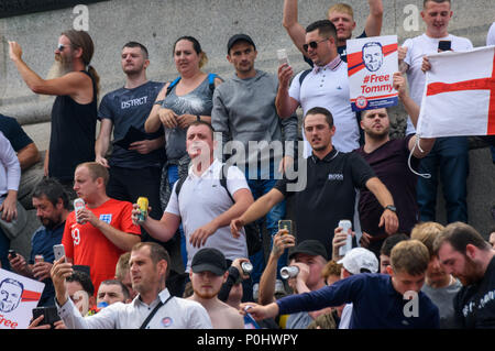 London, UK. June 9th 2018. People on the plinth of Nelson's Column in Trafalgar Square wait  to march to a rally in Whitehall. They hold phones, beer cans, and '#FreeTommy' posters were were chanting and singing for Tommy Robinson, a man who pleaded guilty to contempt of court and whose actions could have led to a trial being stopped, to be freed from jail, claiming his arrest was an attack on free speech. A small counter protest took place a few hundred yards away, with several lines of police keeping the two groups well apart. Peter Marshall/Alamy Live News Credit: Peter Marshall/Alamy Live Stock Photo