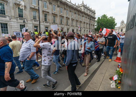 London, UK. June 9th 2018. Several thousand protesters march down from Trafalgar Square to a rally in Whitehall, past flowers laid on the women's memorial for #freeSpeech and #freeTommy and a small line of police horses. An angry crowd stopped in front of Downing Street where two thugs attempted to grab me and pull my camera from my hand to prevent me taking pictures.  I managed to pull away and move through the dense crowd, but they followed me through the mass of people for some distance repeatedly trying to take my cameras and camera bag until I got close to the police and march stewards in