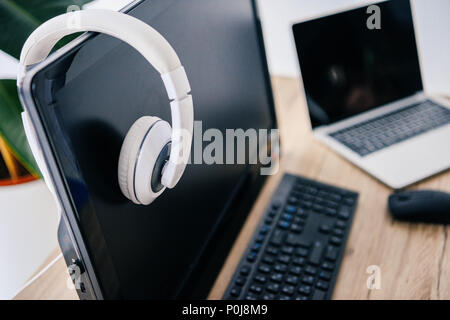 closeup view of headphones on computer and laptop at table Stock Photo
