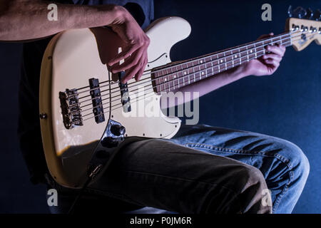 the man plays bass guitar on a black background, the music concept, beautiful lighting on the stage Stock Photo