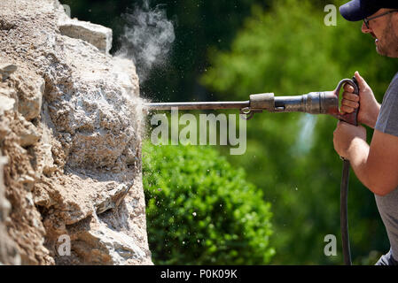 Building worker with jackhammer demolishing a wall, industrial detail Stock Photo