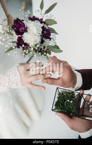 partial view of groom wearing wedding ring on bridal finger Stock Photo