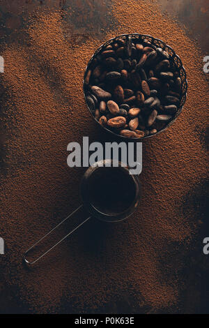 top view of gourmet cocoa beans in vintage bowl and sieve on cocoa powder Stock Photo