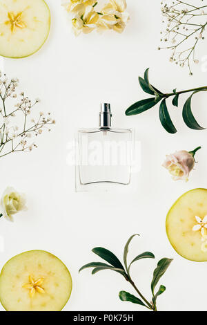 top view of bottle of perfume surrounded with flowers and apple slices on white Stock Photo