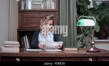 Young woman going through papers and making notes Stock Photo