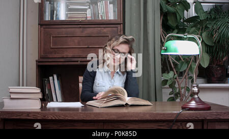 Smiling young woman happily nodding her head while looking for information in a book Stock Photo