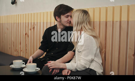 Portrait of young couple in love at a coffee shop, talking and kissing Stock Photo