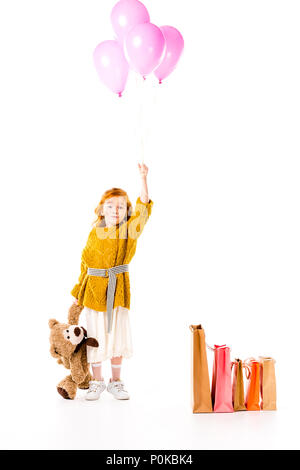 red hair child holding bundle of balloons and teddy bear in hands isolated on white Stock Photo