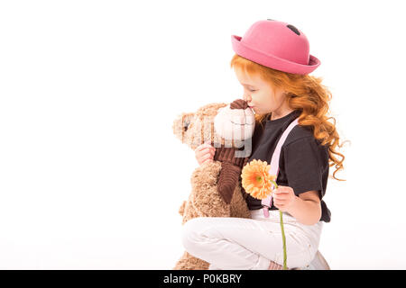 kid holding flower and kissing teddy bear isolated on white Stock Photo