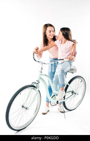 Mother teaching preschooler daughter riding a bicycle isolated on white Stock Photo