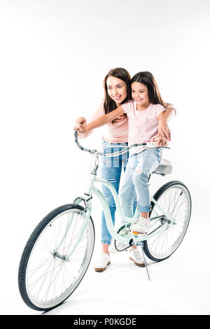 Mother teaching daughter riding a bicycle isolated on white Stock Photo