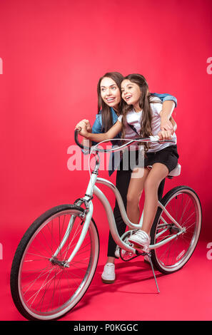 Mother teaching daughter riding a bike on red Stock Photo