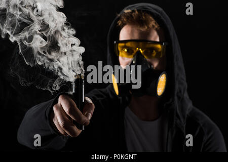 Man wearing protective filter mask activating electronic cigarette Stock  Photo