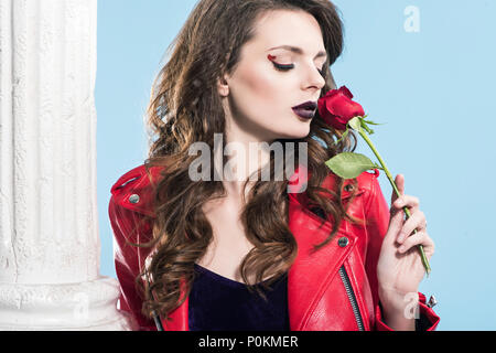 attractive girl sniffing red rose isolated on blue, valentines day concept Stock Photo