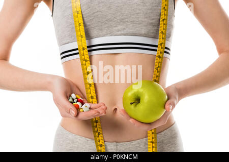 cropped shot of slim woman holding fresh apple and pills isolated on white Stock Photo