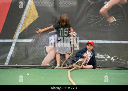 Two children participate in a tug of war contest during a family exhibition day at the 2018 Department of Defense Warrior Games held at the United States Air Force Academy in Colorado Springs, Colorado, on June 3, 2018. The activity formed part of scheduled events for attending families. The archival image documents the moment both competitors fall during the rope pulling game. Stock Photo