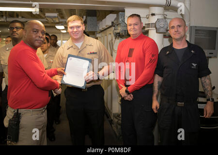 ATLANTIC OCEAN (June 4, 2018) -- Aviation Ordnanceman 2nd Class Zachary Tuttle, from Kewanee, Illinois, assigned to USS Gerald R. Ford’s (CVN 78) weapons department, receives his frocking letter from Cmdr. Travis Davis, Ford's gun boss, during a promotion ceremony in the ship's weapons handling area. Ford is currently underway conducting test and evaluation operations. (U.S. Navy photo by Mass Communication Specialist 3rd Class Joshua Murray) Stock Photo