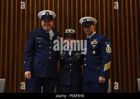 Master Chief Petty Officer James Bach, Rear Adm. Joanna Nunan and Master Chief Petty Officer Jahmal Pereira pose for a photo during the Coast Guard's Ninth District change-of-watch ceremony in Cleveland, June 6, 2018. Pereira assumed the watch from Bach while Nunan presided over the ceremony. Stock Photo