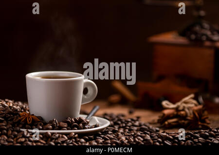 Coffee beans white cup of fragrant coffee and coffee grinder on wooden table on black background Stock Photo