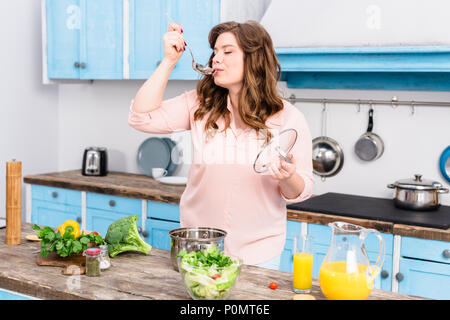 portrait of young overweight woman cooking soup in kitchen at home