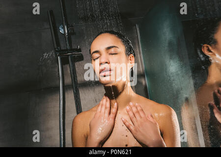 attractive african american woman with closed eyes taking shower Stock Photo