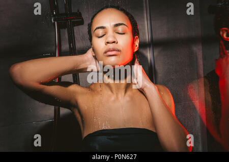 attractive african american woman with closed eyes washing hair in shower Stock Photo