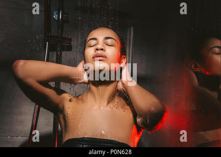 attractive african american woman washing hair in shower Stock Photo